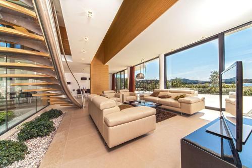 a living room with couches and tables and windows at Golden Rays Luxury Villas & Apartments in Primošten
