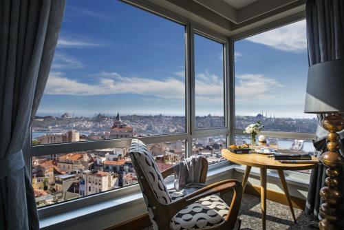 イスタンブールにあるザ マルマラ ペラの窓際のテーブルと椅子が備わるお部屋
