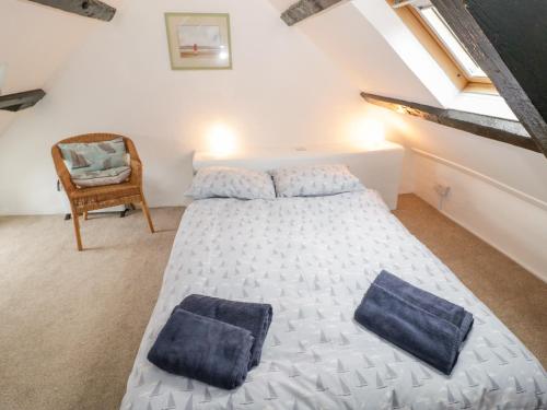 um quarto com uma cama e uma cadeira num sótão em Bron Heulog Cottage em Llangoed