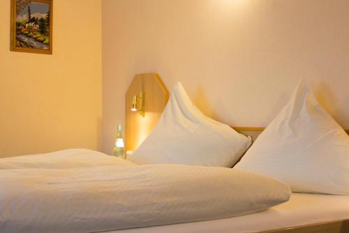 a bed with white sheets and pillows on it at Hotel Restaurant Zur Neroburg in Neroth