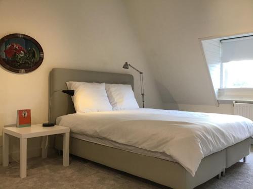 een slaapkamer met een bed en een tafel met een klok bij Brandy’s in Den Haag