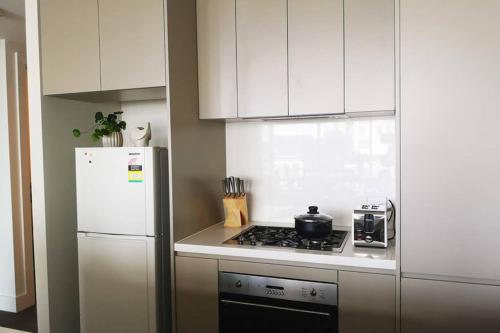 a kitchen with a stove and a white refrigerator at Modern apartment+office w Parking @ Olympic Park in Sydney