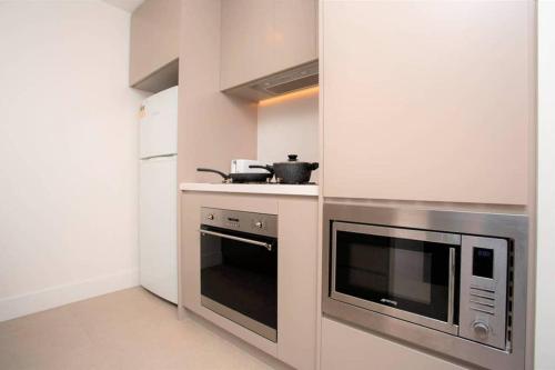 a kitchen with a stove and a microwave at Modern apartment+office w Parking @ Olympic Park in Sydney