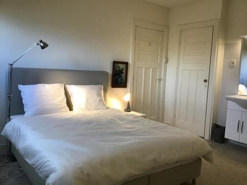 uma cama com lençóis brancos e almofadas num quarto em Brandy’s em Haia