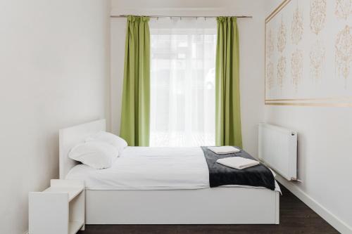 a bedroom with a bed and a window with green curtains at DD Apartments in Cluj-Napoca
