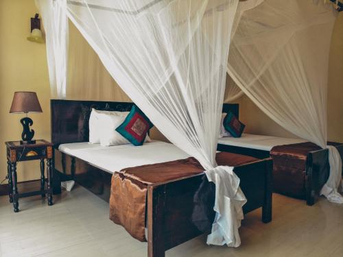 two beds in a room with a canopy at Amaan Beach Bungalows in Nungwi
