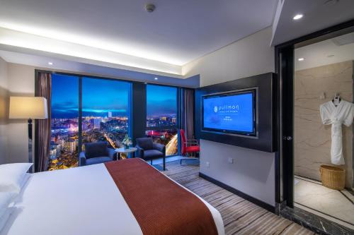 um quarto de hotel com uma cama grande e uma televisão de ecrã plano em Pullman Guiyang em Guiyang