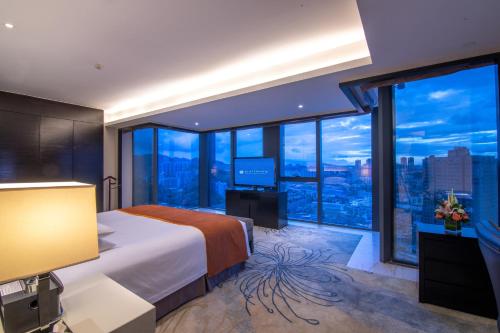 a bedroom with a large bed and large windows at Pullman Guiyang in Guiyang