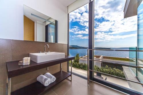 a bathroom with a sink and a view of the water at Golden Rays Luxury Villas & Apartments in Primošten