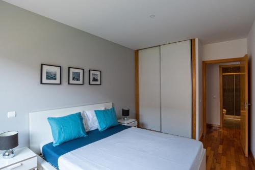een slaapkamer met een groot wit bed met blauwe kussens bij Matosinhos Relax and Fun by PortoProperties4You in Matosinhos