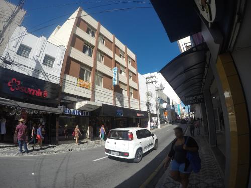 a white car parked on the side of a city street at Hotel Sao Nicolau in Taubaté