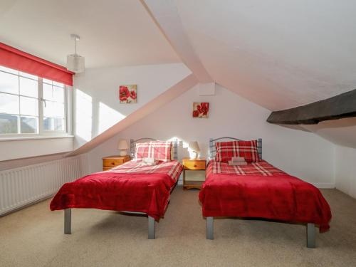 - 2 lits dans une chambre mansardée avec des draps rouges dans l'établissement Fountain Cottage, à Keswick