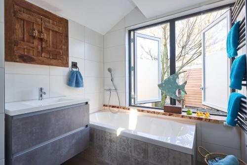 Un baño con bañera, lavabo y ventana. en Family home, en Edam