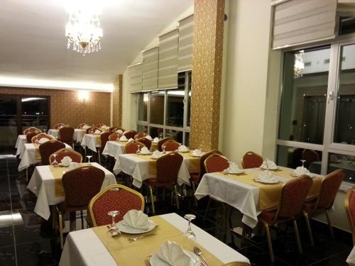 Gevher Hotel في قيصري: غرفة طعام بها طاولات وكراسي وثريا