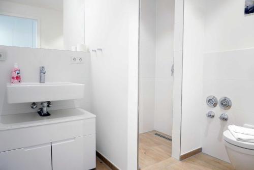 a white bathroom with a sink and a toilet at Baabe Villen Ensemble FeWo 32 Meer in Baabe