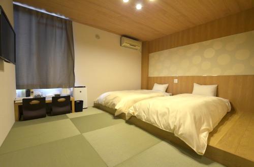 a bedroom with two beds and a window at Isahaya Daiichi Hotel in Isahaya
