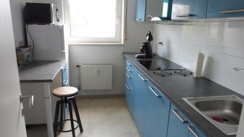 KEHL Center Schöne 2 Zimmer Wohnung mit Terrasse 60M2 في كيهل آم راين: مطبخ مع دواليب زرقاء ومغسلة ومقلاه