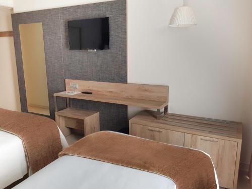 a room with two beds and a desk and a tv at Cesar Augustus in Cambrils
