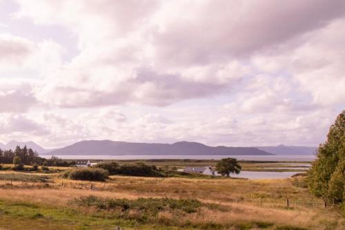 a field with a lake and mountains in the distance at Breakish Bay Pods in Breakish