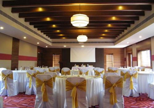 a banquet hall with white tables and chairs with bows at Poetree Thekkady in Thekkady