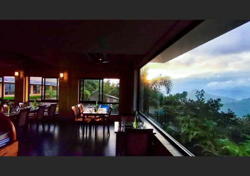 a room with tables and chairs and a large window at Poetree Thekkady in Thekkady