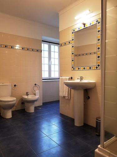 a bathroom with a sink and a toilet and a mirror at Casa do Arco in Sintra
