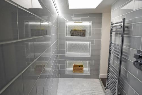 een badkamer met grijze betegelde muren en een inloopdouche bij Toothbrush Apartments - Central Ipswich - Fore St in Ipswich