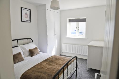 een witte slaapkamer met een bed en een raam bij Toothbrush Apartments - Central Ipswich - Fore St in Ipswich