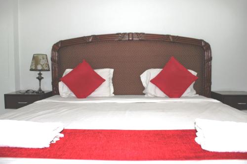 a bed with two red pillows on top of it at p p motel in Alibaug