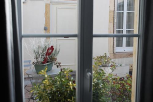 an open window looking out onto a patio with plants at Hotel Le Jacquemart in Dijon