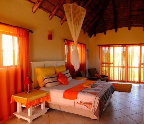 a bedroom with a large bed with orange curtains at Baobab - NUDE - SunEden Family Naturist Resort in Pretoria