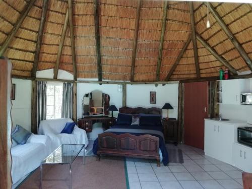 a bedroom with a bed and a couch in a room at Clarens socialites, Thatch Cottage #1 in Bethlehem