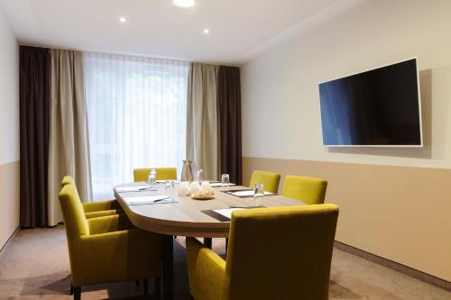 a dining room with a table and yellow chairs at Steigenberger Parkhotel Braunschweig in Braunschweig