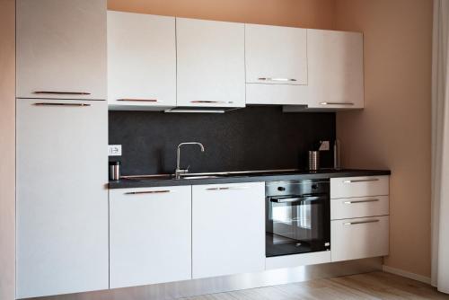 a white kitchen with white cabinets and a sink at Appartamenti Villa Gloria in Peschiera del Garda