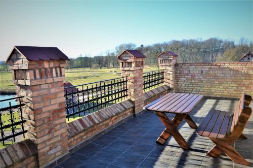 a wooden bench sitting on a patio with a brick wall at Folwark Pszczew in Pszczew