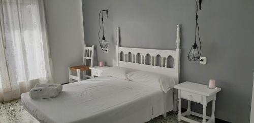 ein weißes Schlafzimmer mit einem weißen Bett und 2 Tischen in der Unterkunft El Pas, Apartamento con vistas al mar L1 in Port de la Selva