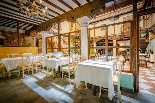 un comedor con mesas y sillas blancas en Hotel Spa La Casa del Rector Almagro, en Almagro