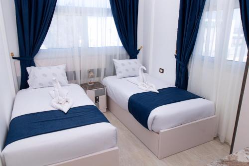 two beds in a small room with blue curtains at Swiss Royal DAHAB in Dahab