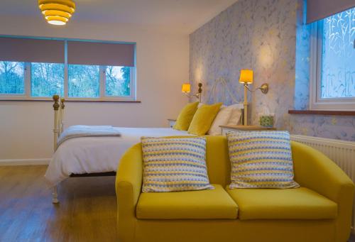 a bedroom with a bed and a yellow couch at Blyth Lodge B&B in Halesworth