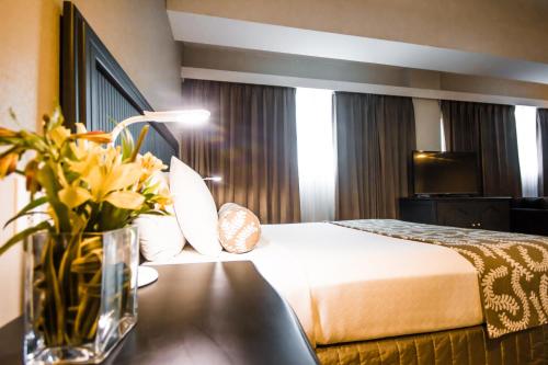 a hotel room with a bed and a table with flowers at Crowne Plaza Managua by IHG in Managua