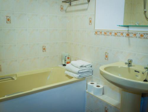 uma casa de banho com uma banheira, um lavatório e toalhas em Blyth Lodge B&B em Halesworth