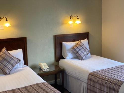 a hotel room with two beds and a phone at The Hand Hotel Llangollen by Compass Hospitality in Llangollen