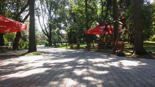 a path in a park with trees and red umbrellas at Hotel Kakadu in Konin