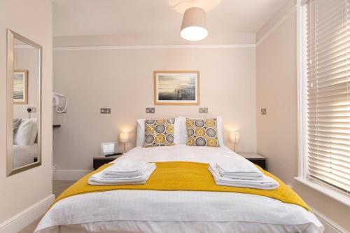 a white bedroom with a large bed with yellow blanket at Redhouse in Salisbury