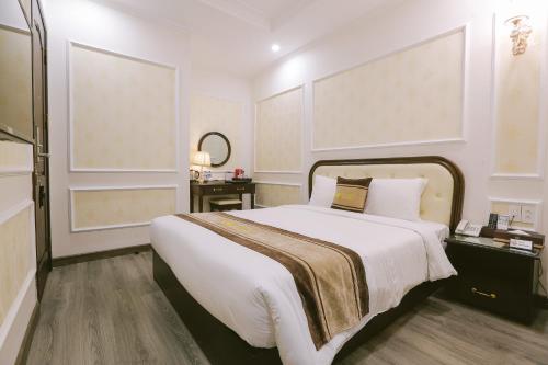 a bedroom with a large white bed and a mirror at Vincent Halong Hotel in Ha Long