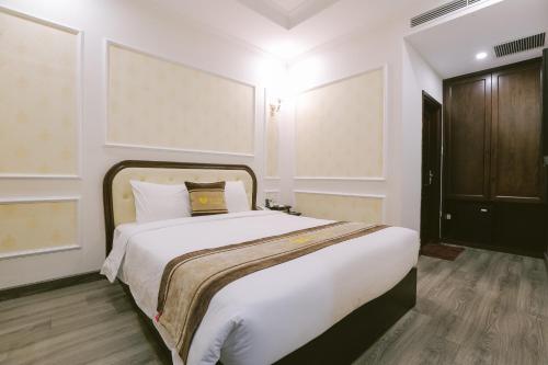 a bedroom with a large bed with white sheets at Vincent Halong Hotel in Ha Long