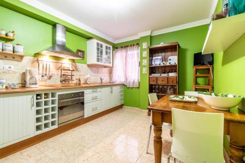 a kitchen with green walls and a wooden table at Flatguest Ingenio + 2 Bdr + Wifi + 4PAX in Ingenio