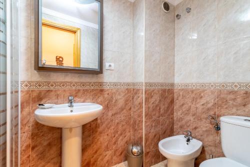 a bathroom with a sink and a toilet and a mirror at Flatguest Ingenio + 2 Bdr + Wifi + 4PAX in Ingenio