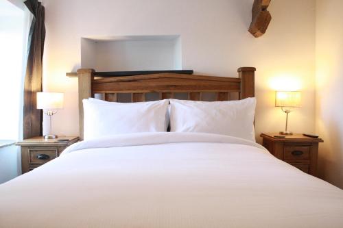 a bedroom with a large white bed with two lamps at The Black Dog Inn in Dalton in Furness