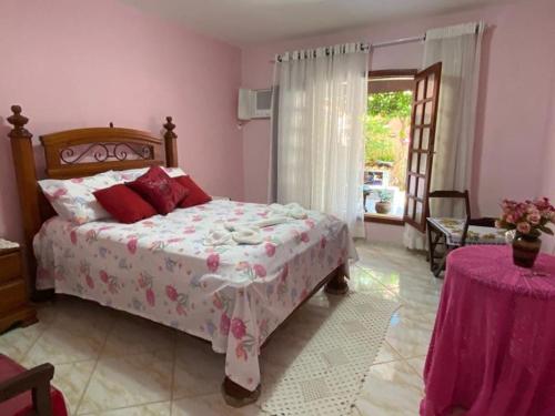 Un dormitorio con una cama y una mesa y una ventana. en Cantinho da tia Lira, en Cabo Frío